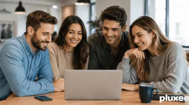 Un equipo de trabajo sonriente y colaborativo reunido alrededor de una computadora portátil en una oficina, demostrando compromiso laboral.