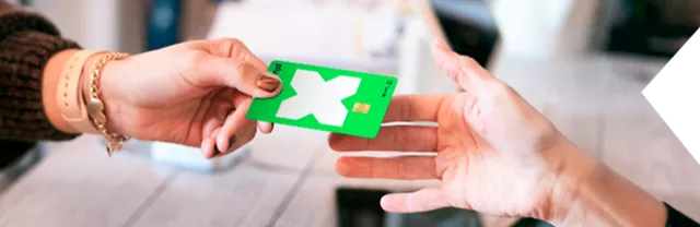 Manos intercambiando las tarjetas de vales de despensa Pluxee Tienda